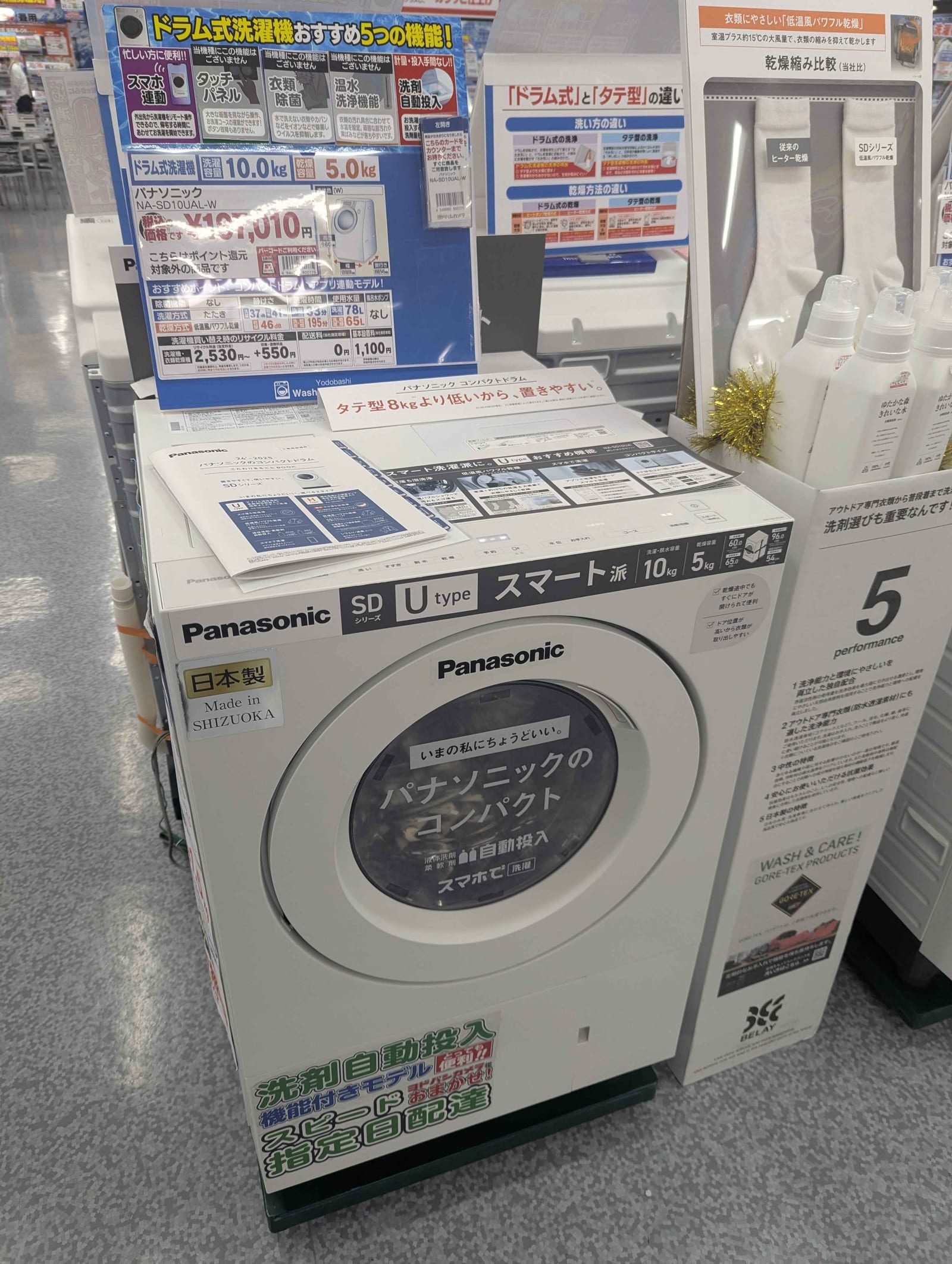 A modern front-load washing machine with a digital display on show in an electronics store.